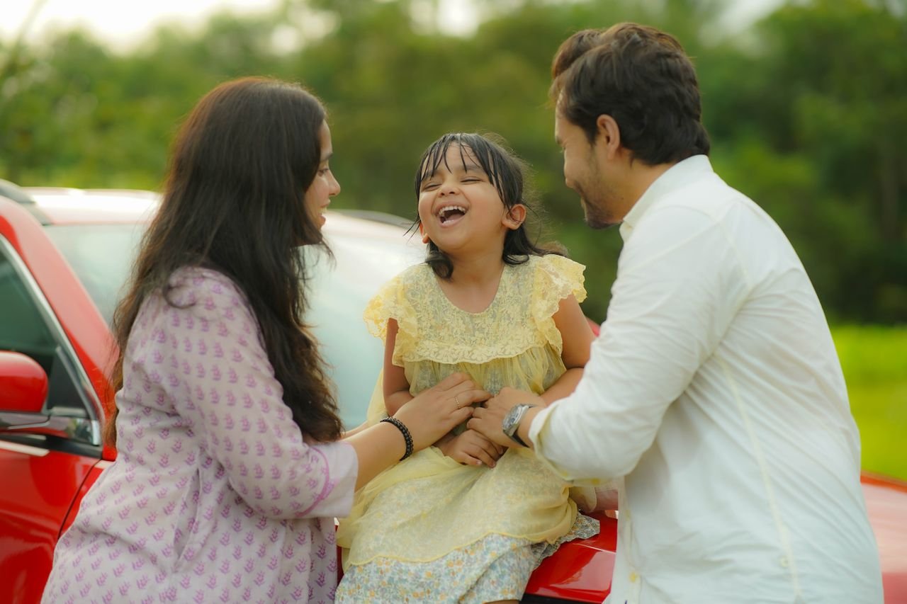 Home A cheerful family moment with a child laughing outdoors on a sunny day.